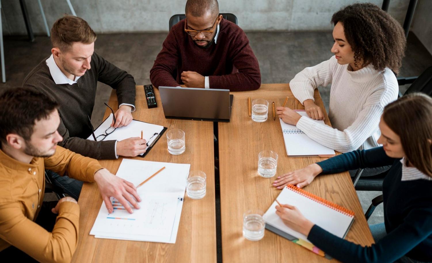 Espace de travail moderne avec équipe collaborative discutant stratégie de financement
